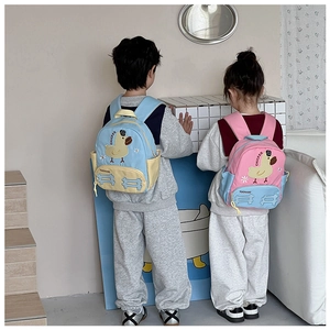Detail view of pink and blue cartoon duck backpacks on children in a cozy room