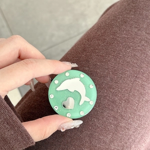 Detail of mint green phone socket with rhinestone border and dolphin motif on a hand