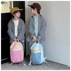 Detail of color-block kids backpacks featuring front zipper pockets and durable canvas material