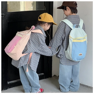 Side view of children carrying pink and blue color-blocked nylon backpacks in a park