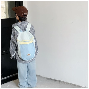 Detail of light blue kids backpack with mountain logo label and yellow zipper accents
