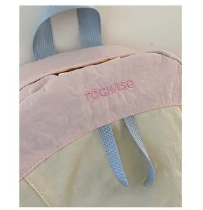 Detail of embroidered brand logo on pink and beige nylon school backpack