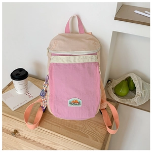 Detail of pink and beige kids backpack with woven rope charm and TOCHASO logo tag