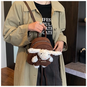 Detail of a brown suede mini backpack with a 3D plush bunny and slim leather straps
