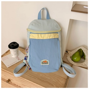 Close-up of color-block children backpack with TOCHASO label on a wooden desk