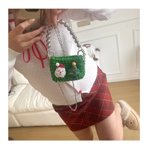 Close-up of green knitted mini bag featuring Santa Claus embroidery and silver beaded handle