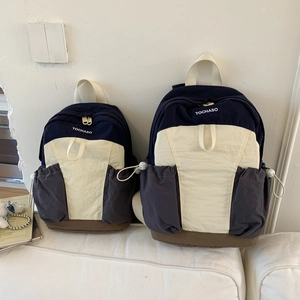 Comparison of large and small color-block backpacks on a sofa in a home setting