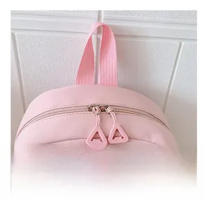 Detail of pink canvas backpack showing smooth dual zippers and top handle for students