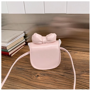 Close-up of pink mini bag with bow accent, white lace trim and faux leather texture