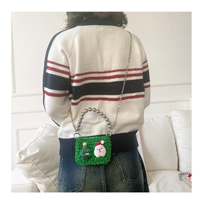 Detailed back view of a green crochet Christmas handbag with silver beads on a girl