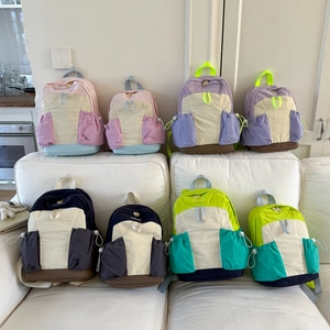 Detail view of colorful nylon backpacks in various sizes and color-block designs on a sofa