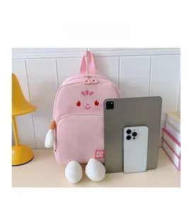 Pink cartoon school backpack shown next to a tablet and phone for size comparison