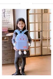 Blue kids backpack with cartoon face detail and soft 3D limbs shown on young model
