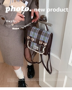 Close-up of retro plaid backpack with lace trim and handmade label hanging on a door