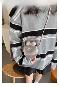 Detail of child's mini crossbody bag with silver finish and pink lace trim accents