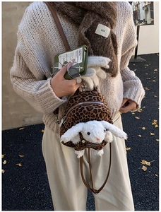 Detail shot of mini leopard print backpack featuring a cute white plush bunny accessory