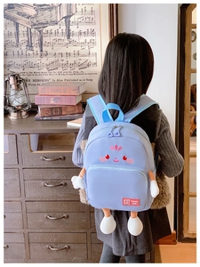 Detail of light blue school backpack featuring cute cartoon embroidery and soft 3D limbs