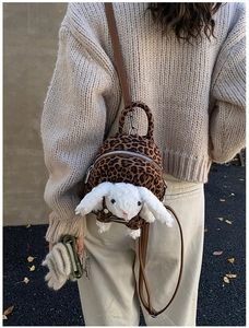 Close-up of leopard print backpack with white plush bunny ears and brown leather straps