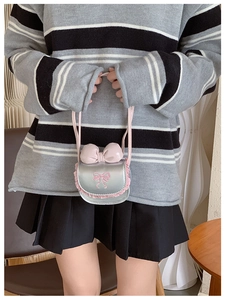 Detail of a sweet girls' mini shoulder bag with pink lace trim and bow decoration