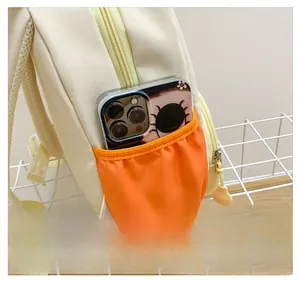 Détail de la poche latérale élastique orange sur le sac à dos blanc en toile pour enfant