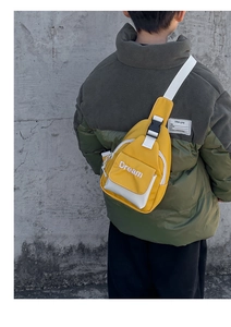 Outdoor shot of a kids yellow crossbody chest bag with Dream text on urban street background
