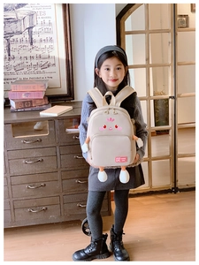 Detail view of large-capacity cartoon school bag with plush 3D limbs and red logo tag