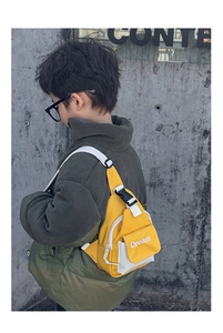 Detail view of bright yellow kids crossbody bag with white Dream embroidery on nylon