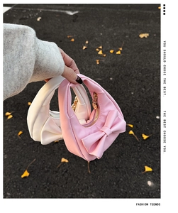 Close-up of mini PU leather handbags with oversized bows and gold heart-shaped zippers