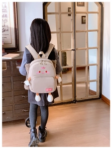 Detailed view of cream-colored kids backpack with cute cartoon face and plush 3D limbs