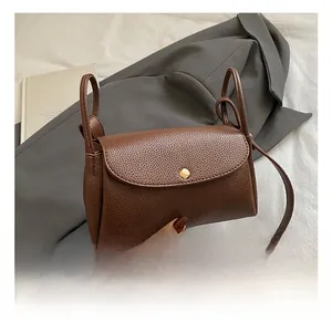 Close-up of dark brown lychee leather crossbody bag with a gold metal clasp and knotted handle