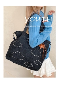 Detail of black denim tote bag with cloud embroidery and brown star leather charm
