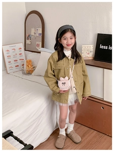 Detailed view of child fashion outfit featuring khaki jacket, mesh skirt and pink bow bag