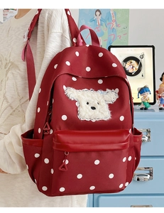 Sac à dos rouge à pois avec écusson chiot en peluche dans un décor de style écolier