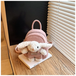 Close-up of pink plush bunny backpack on wooden table with detailed soft texture