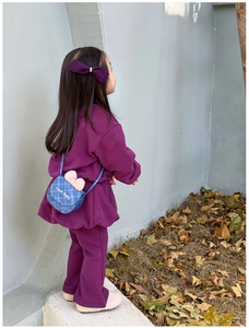 Petite fille portant un mini sac bandoulière en denim avec nœud rose et motif matelassé.