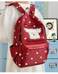 Détail du sac à dos rouge à pois avec écusson chiot en peluche blanc et poche latérale