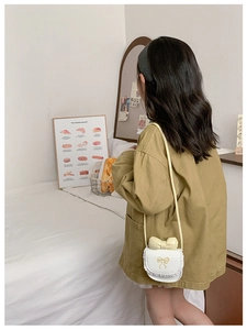 Close-up of white leather kids crossbody bag with yellow bow and lace details