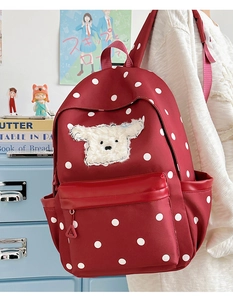 Détail du sac à dos rouge à pois avec écusson chiot en peluche et poches multiples
