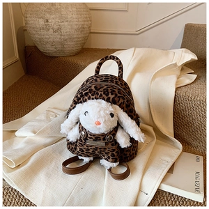 Detail of leopard print backpack featuring a cute plush bunny doll with matching overalls