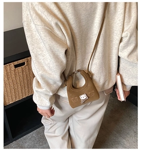 Close-up of a mini brown bear bag with a plush bear head and black checkered bow accent