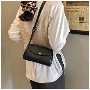 Detail of black pebbled leather crossbody bag with gold snap button and adjustable strap