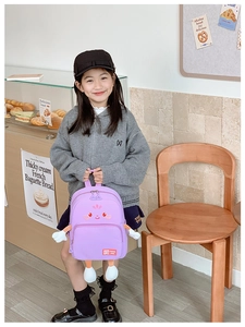 Detail of purple cartoon kids backpack with cute 3D limbs in a warm bakery setting
