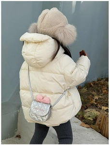 Mini sac bandoulière argenté matelassé avec nœud rose porté par un enfant en hiver