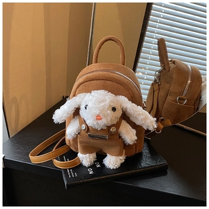Close-up of a brown suede backpack featuring a cute white plush bunny doll with overalls
