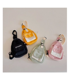 Flat lay view of four colorful canvas crossbody chest bags for kids with Dream text logo