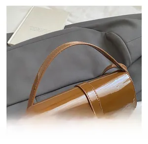 Close-up of glossy brown patent leather shoulder bag with sleek gold metallic lock detail