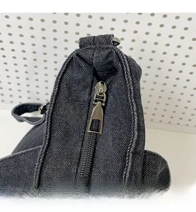 Detailed view of the smooth metal zipper and textured dark denim fabric on large tote bag