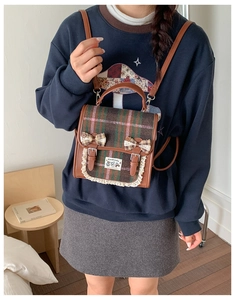 Detail of vintage plaid backpack with lace bows and brown leather straps on model