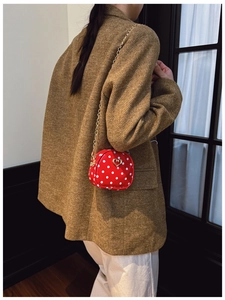 Detail einer roten gepunkteten Kindertasche mit Herz-Verschluss und Goldkette am Model