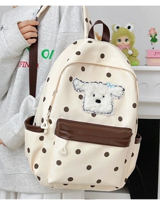 Détail de broderie chiot mignon et poche en cuir marron sur sac à dos enfant à pois